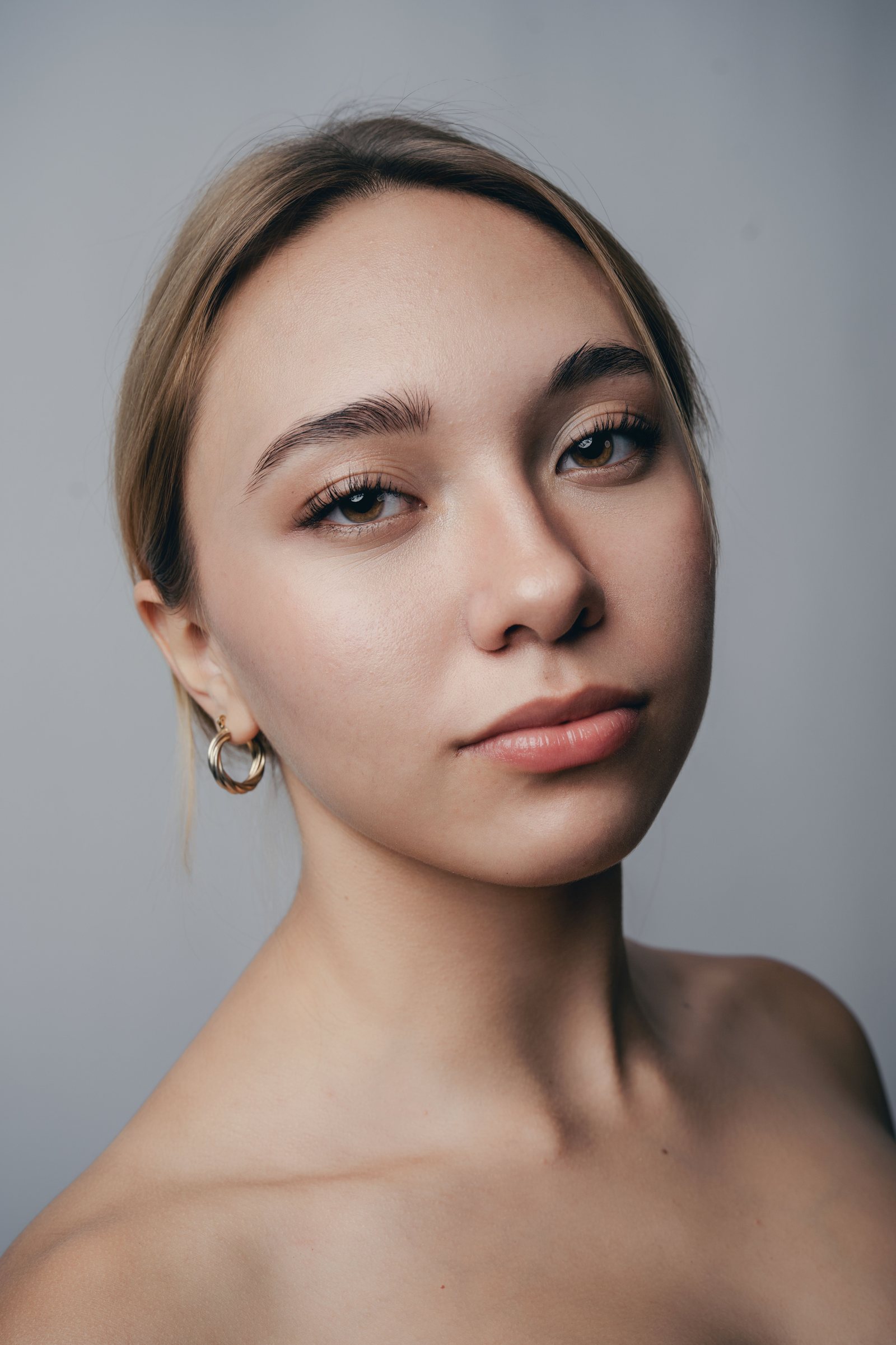 Retrato de uma mulher olhando para a câmera, em luz natural difusa sobre fundo cinza claro