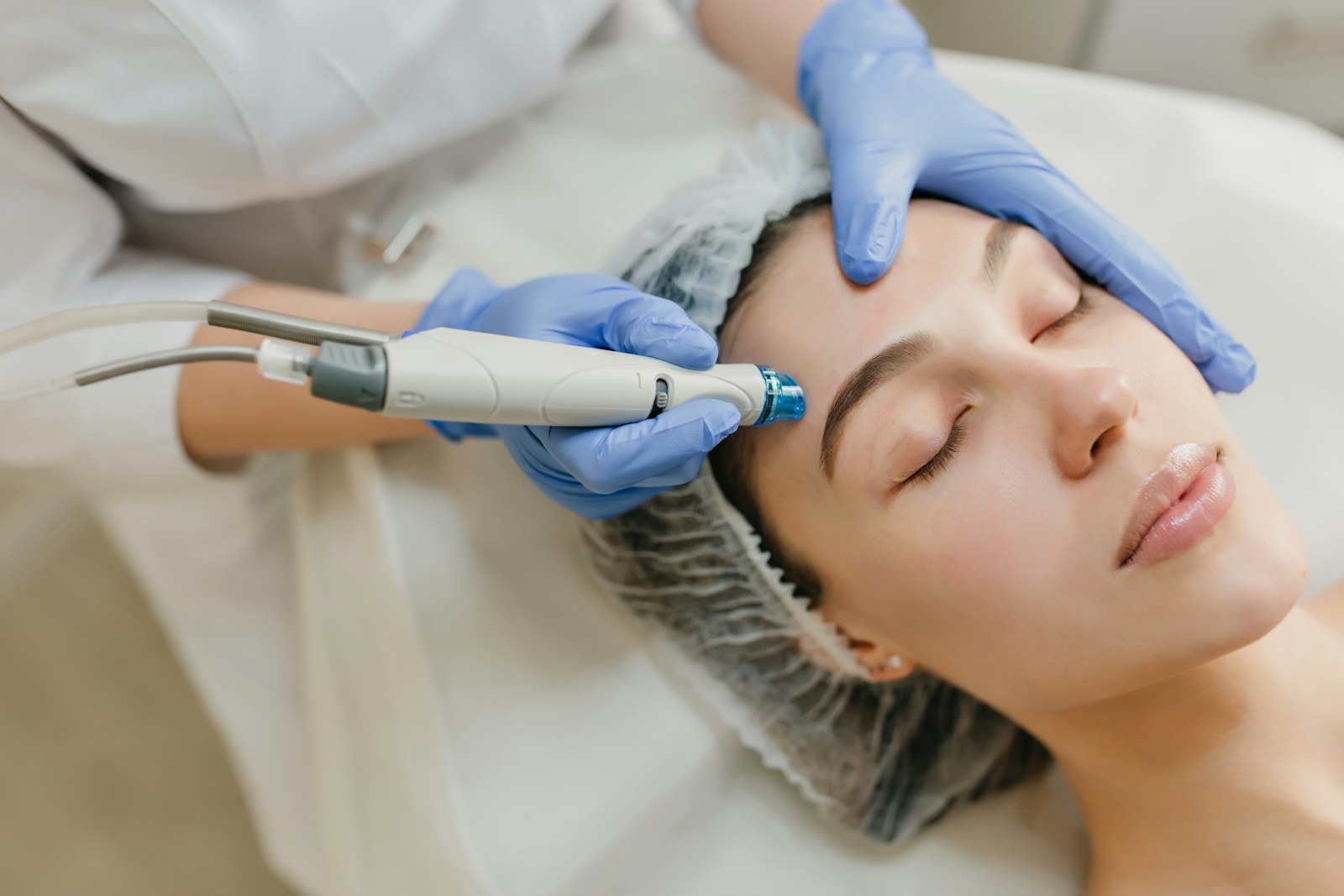 Médica aplicando tratamento a laser na testa de uma paciente deitada